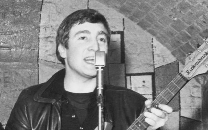 December 1961: Singer, guitarist and songwriter John Lennon (1940 - 1980) of the British group The Beatles live on stage at the Cavern Club in Matthew Street, Liverpool. (Photo by Evening Standard/Getty Images)